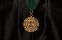 Gold Medal with Marywood seal hanging from a green ribbon against black academic attire Marywood University Awards 39 Endowed Medals of Recognition to Graduates