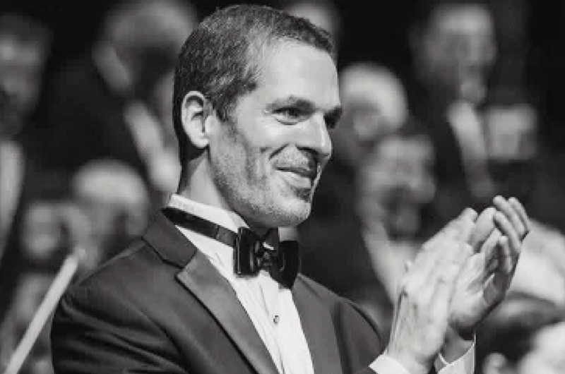 Black and white photo of a man in a tuxedo clapping