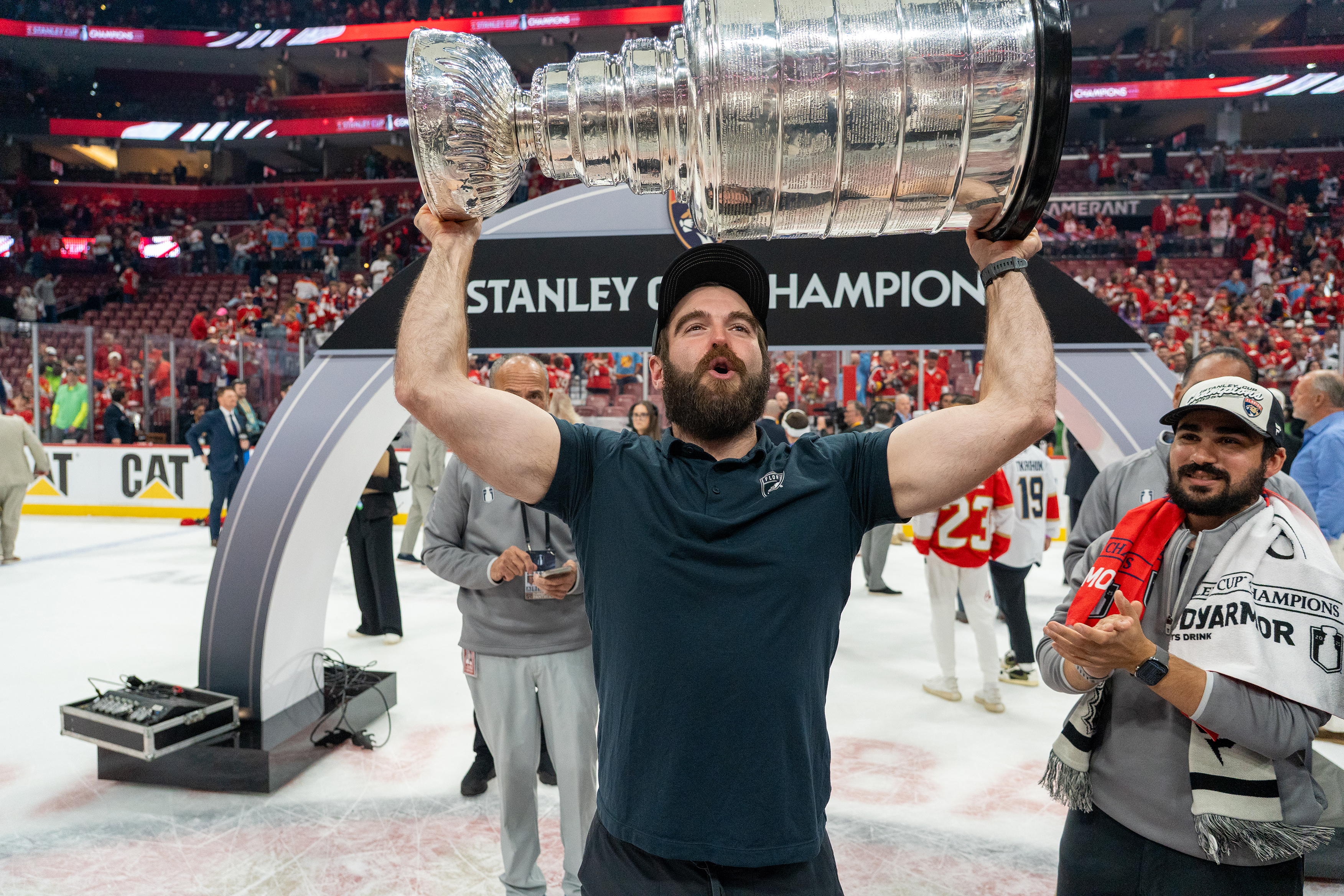 Man with a beard holding the silver Stanley Cup in an ice rink.