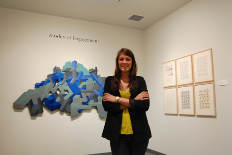 woman standing in front of her artwork on wall