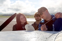 students learning how to check oil on plane with instructor showing them Soaring Beyond Limits – Business Careers in Aviation and Global Trade