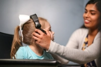 A female student places a set of headphones over the ears of a young child Transforming Lives Through Speech Language Pathology | Accredited, Hands-On Program at Marywood University