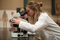 A female student in a white lab coat looks into a microscope. Launch Your Medical Career with Confidence | Accredited Physician Assistant Master’s Program at Marywood University
