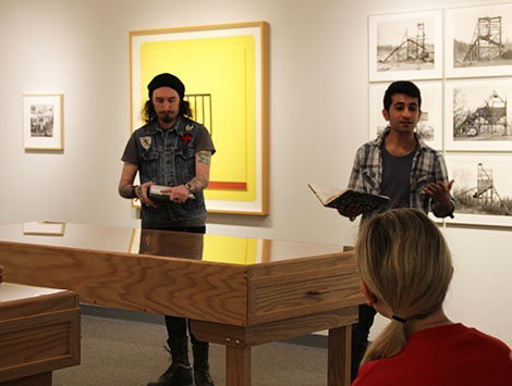 people giving gallery talk with artwork on wall in background