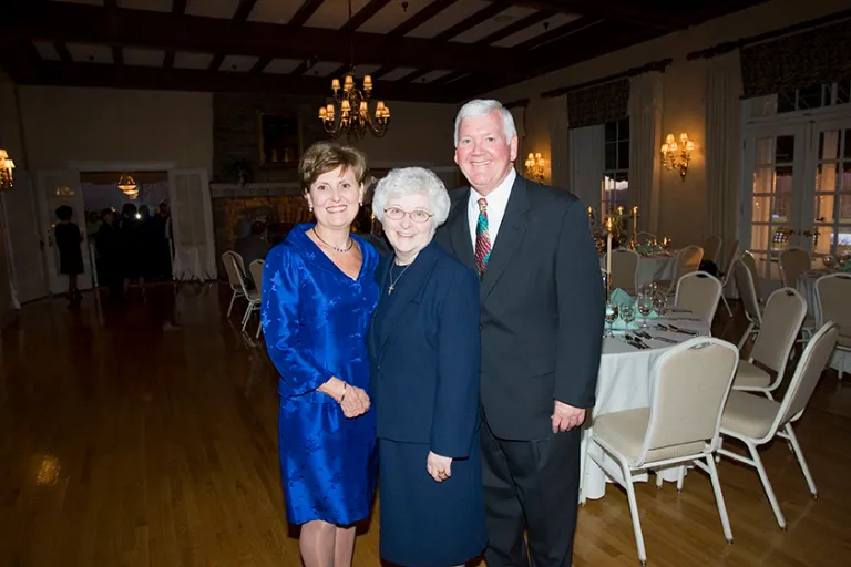 man with two women dressed nicely smiling for photo